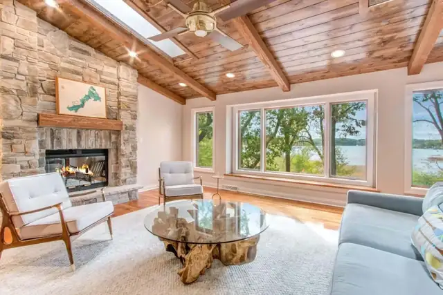 Lake Beulah living room with stacked stone fireplace, wood plank vaulted ceiling and wide lake-view windows
