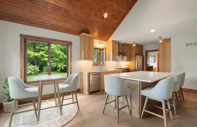 Kitchen and dining area with knotty pine vaulted ceiling, wood cabinets, quartz island and round breakfast table